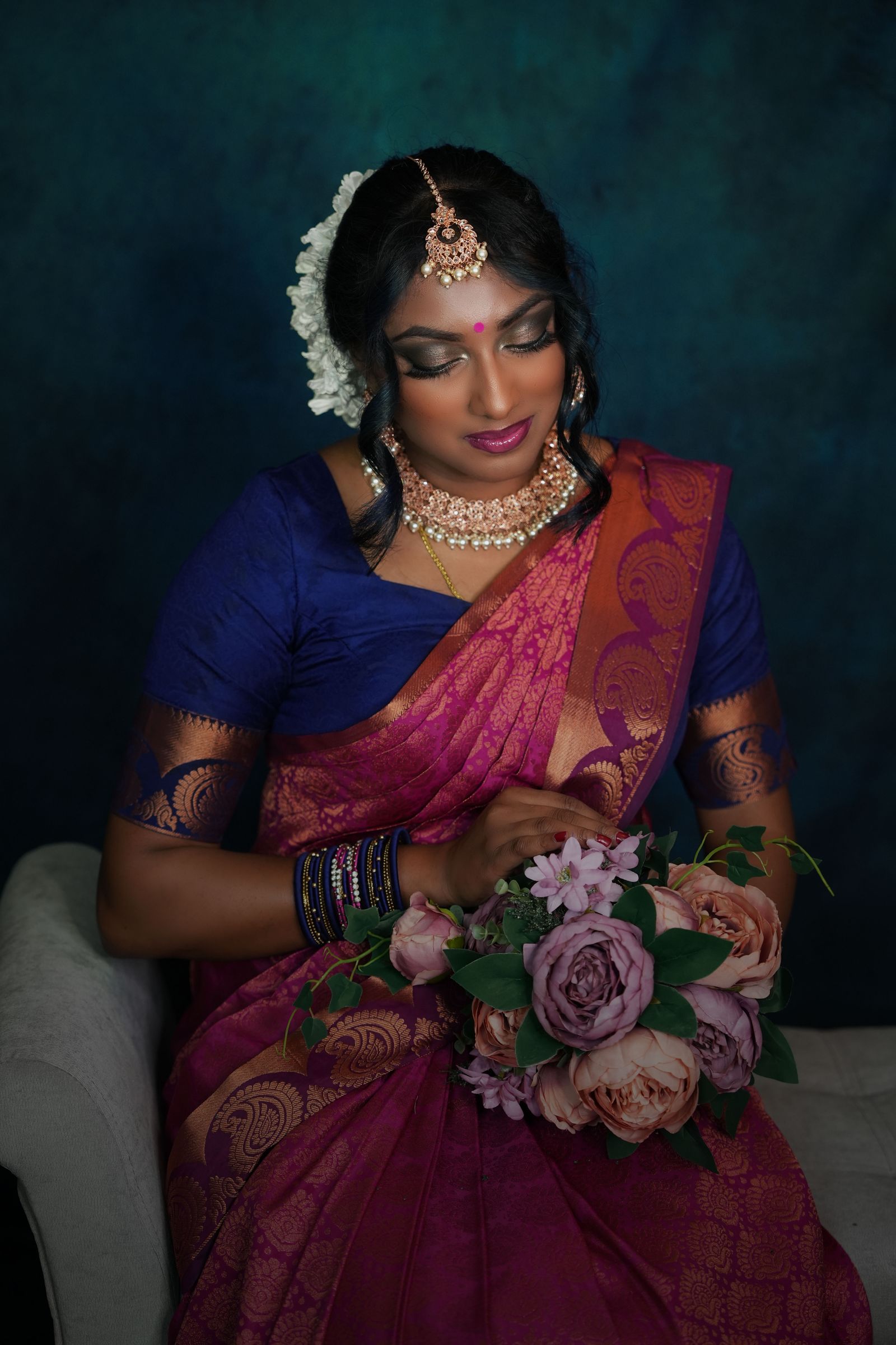 Tamilische Braut mit Blumenstrauß in einem farbenreichen Sari.